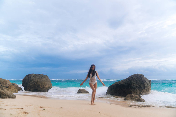 Sexy tanned girl in swimsuit posing on rocky beach - Φωτογραφία, εικόνα