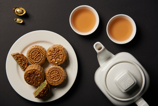 felülnézet mooncakes, csészék és elszigetelt fekete tea-pot - Fotó, kép