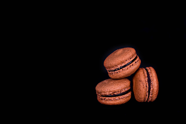 Macarons cookies sur un fond sombre. Biscuits macarons doux et colorés tour sur fond sombre avec espace vide, mise au point sélective
 - Photo, image