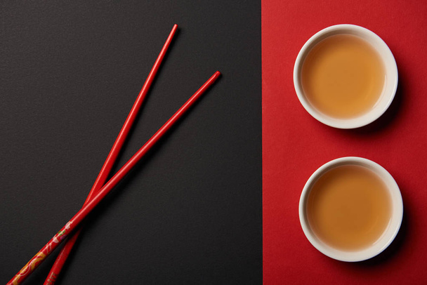 top view of chopsticks with traditional chinese tea on red and black background - Фото, зображення