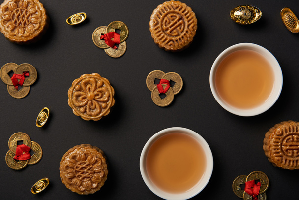 a hagyományos mooncakes, a teáscsészét és a feng shui érmék elszigetelt fekete felülnézet - Fotó, kép