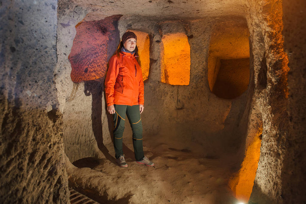 Beautiful tourist woman explore long narrow tunnel in ancient Kaymakli underground cave city. Travel to Turkey - Zdjęcie, obraz
