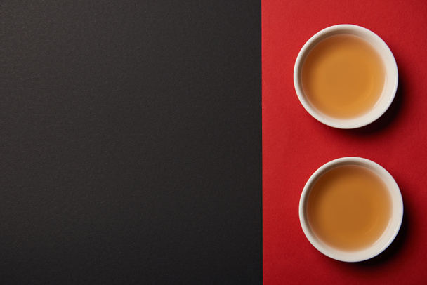 top view of tea cups on red and black background with copy space - 写真・画像