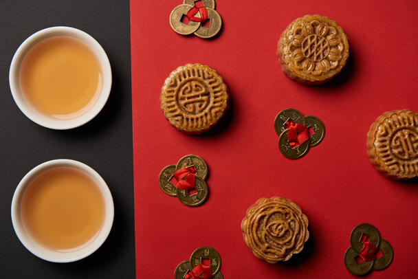 vue du dessus de mooncakes, feng shui pièces et tasses avec thé sur fond rouge et noir
 - Photo, image