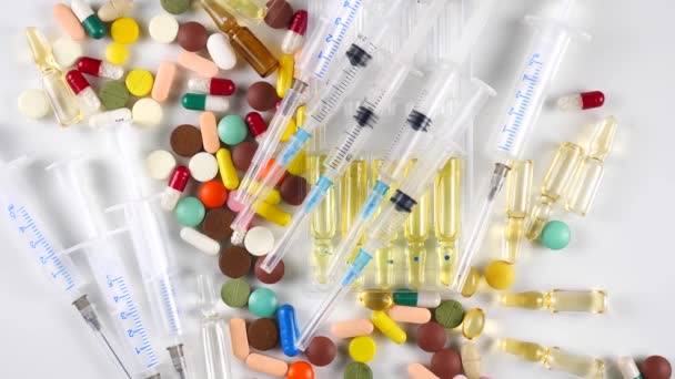 Jeringas médicas y tabletas multicolores giran sobre la mesa
 - Metraje, vídeo