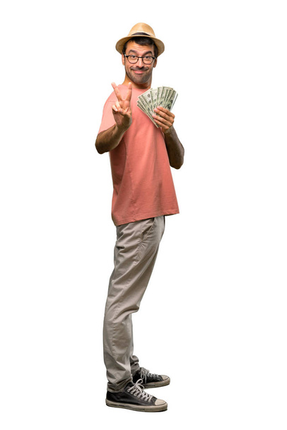 Man holding many bills smiling and showing victory sign on isolated white background - 写真・画像