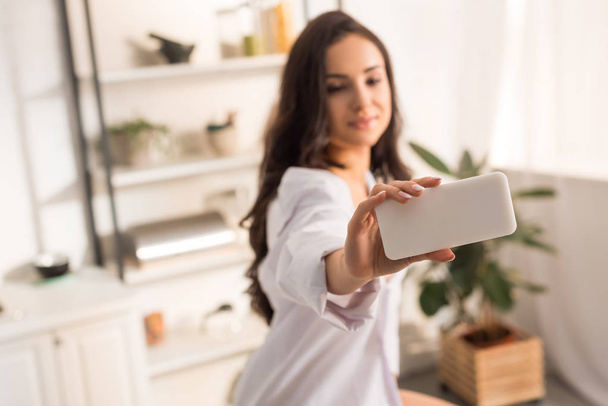 woman in white shirt taking selfie on smartphone at home in morning - Valokuva, kuva