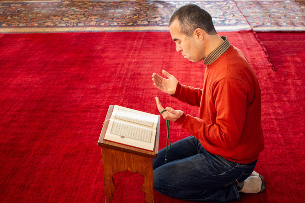 イスラム教徒の男性のモスクでコーランを読む - 写真・画像