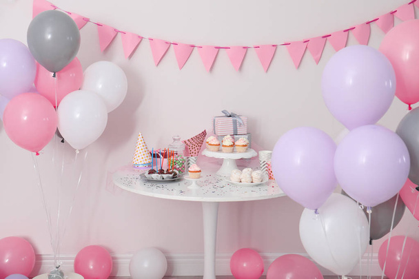 Gâteries de fête et articles sur la table dans la chambre décorée de ballons
 - Photo, image