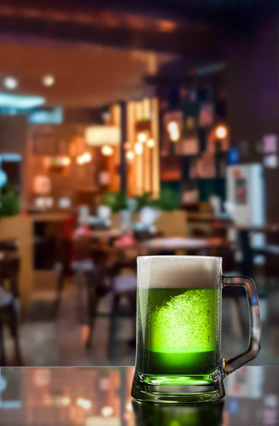 Lasi tuoretta kylmää vihreää olutta puisessa baaritiskillä pubissa
. - Valokuva, kuva