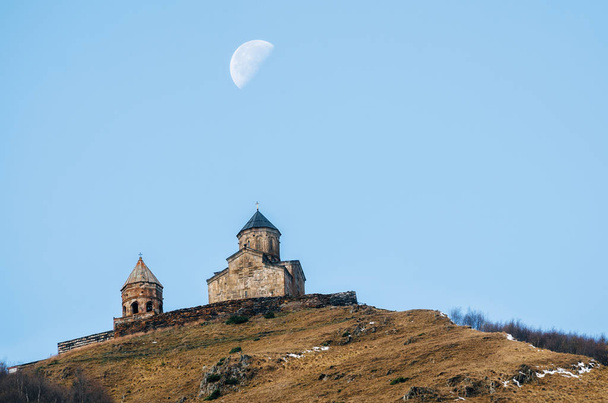 Kafkas Dağları, eski Gergeti Trinity Tsminda Sameba mavi gökyüzü ve supermoon, Georgia işareti karşı kilise - Fotoğraf, Görsel