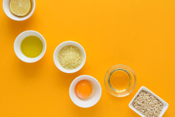 Fresh ingredients for homemade effective acne remedies on yellow background. Honey, sea salt, egg yolk, olive oil, oat, lemon and aloe. Flat lay. Copy space - Fotografie, Obrázek