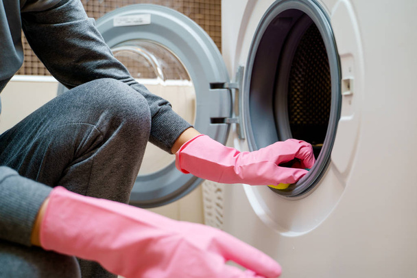Image of woman s hand in pink rubber glove washing washing machine - Photo, Image
