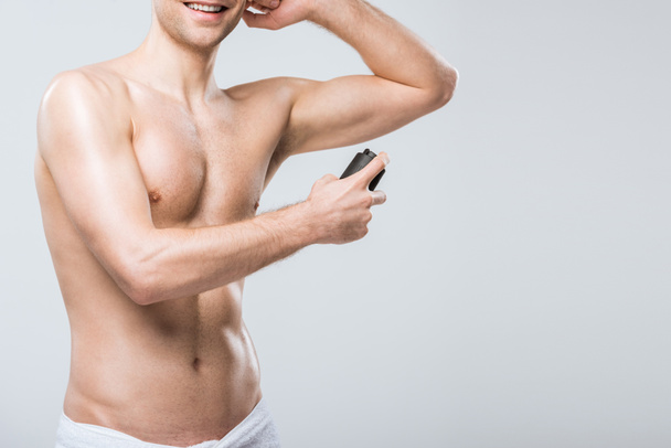 cropped view of smiling shirtless man spraying deodorant, isolated on grey - Foto, Imagen