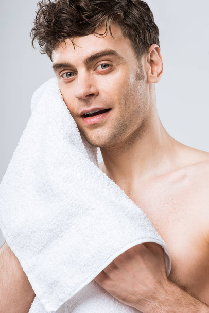 Красивый молодой человек, вытирая белым полотенцем изолированы на серый
 - Фото, изображение