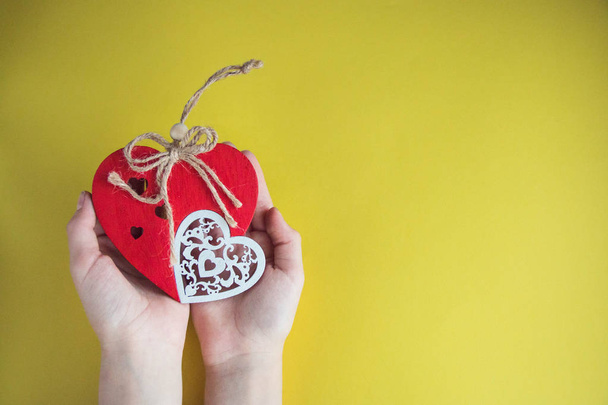handmade red heart in hands close-up on yellow background, symbol of love, happy Valentine's day. - Fotoğraf, Görsel