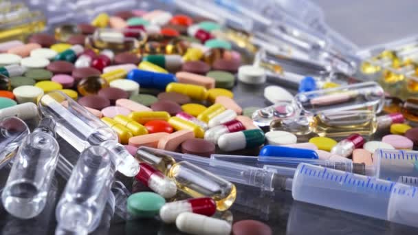 Jeringas médicas y tabletas multicolores giran sobre la mesa
 - Imágenes, Vídeo