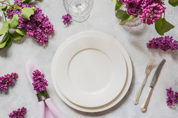 Spring table place setting with lilac flowers, silverware on light table. Top view. - Fotoğraf, Görsel