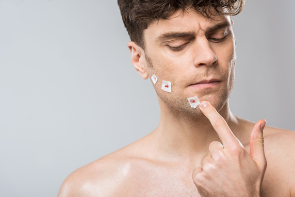 handsome man touching face after bad shaving, isolated on grey - Foto, imagen