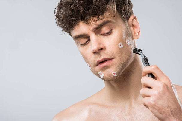 handsome man with razor after bad shaving, isolated on grey - Foto, Imagen