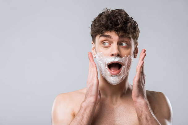 shocked man yelling with shaving foam on face, isolated on grey - Photo, Image