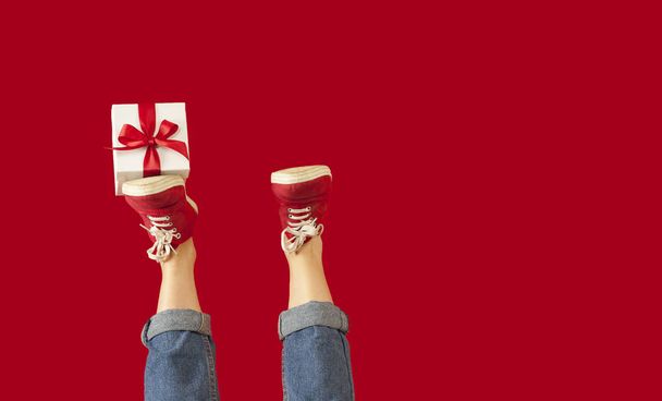 feet with a gift for the holidays on an isolated red background, a girl with a gift, giving gifts, discounts. Lovers day concept,Valentine's Day. - Foto, afbeelding