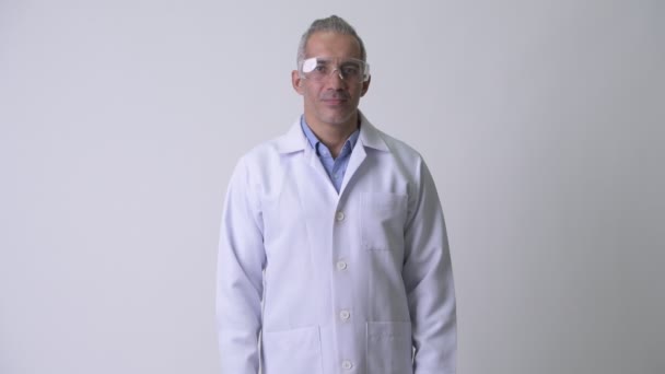 Handsome Persian man doctor wearing protective glasses against white background - Materiaali, video
