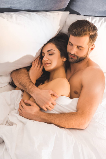 beautiful nude couple embracing while sleeping in bed  - Foto, afbeelding