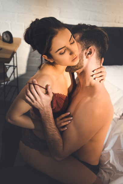beautiful sexy couple passionately embracing on bed at home - Foto, Imagem