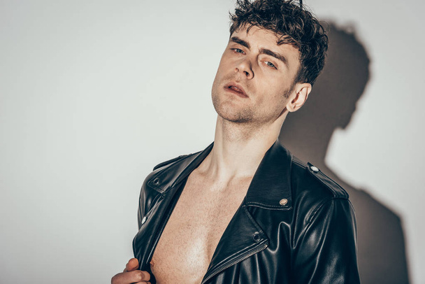 handsome sexy shirtless man posing in black leather jacket on grey - Photo, Image