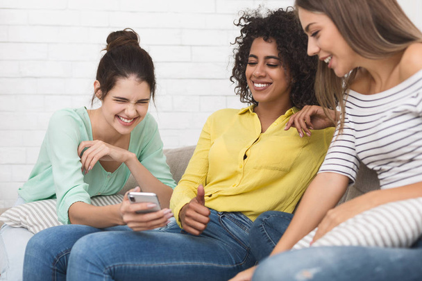 Woman showing funny content on smartphone to friends - Photo, Image