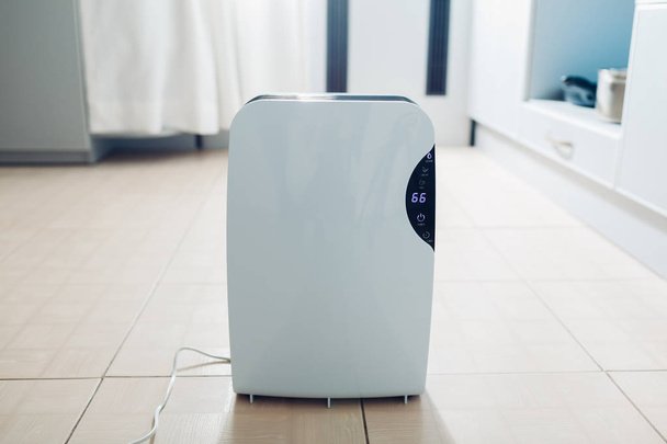 Desumidificador com painel de toque, indicador de umidade, lâmpada UV, ionizador de ar, recipiente de água funciona em casa na cozinha. Secador de ar
 - Foto, Imagem
