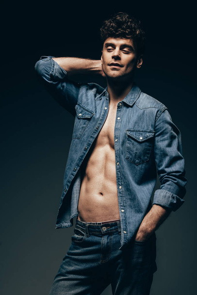 handsome young man posing in denim clothes isolated on dark grey - Foto, Imagem