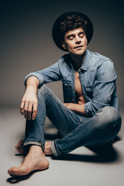 stylish young man posing in jeans clothes and hat on dark grey - Foto, Imagem