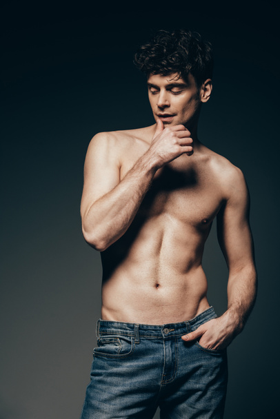 handsome tender man in jeans posing isolated on dark grey - Zdjęcie, obraz