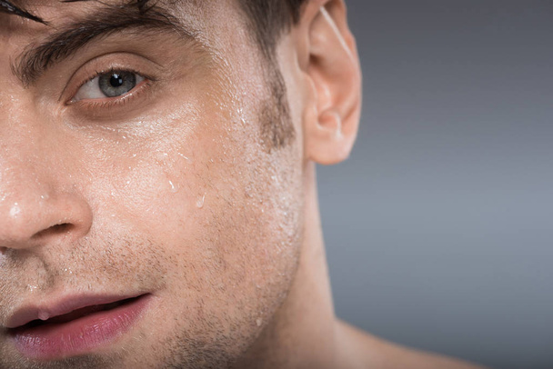 handsome young man with water drops on face, isolated on grey - Foto, Imagem