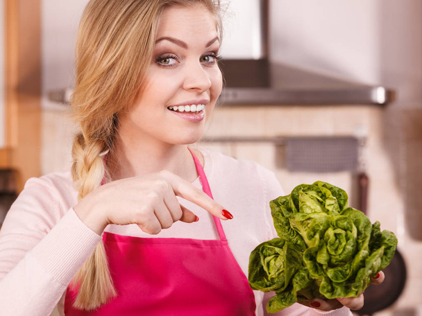 Happy young woman, cooking chef showing holding green lettuce. Female loving vegetables about to cook. - Photo, Image