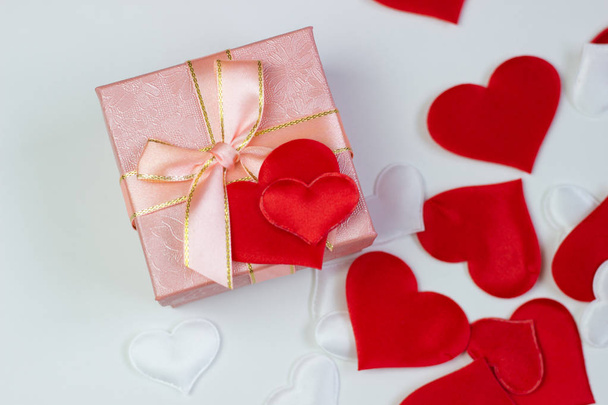Un regalo en una hermosa caja y corazones son rojos y blancos. San Valentín, Día Internacional de la Mujer
. - Foto, imagen