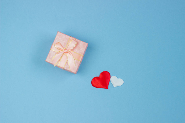 A gift in a beautiful box and hearts are red and white on a blue background. Valentine's Day, International Women's Day. - Photo, image