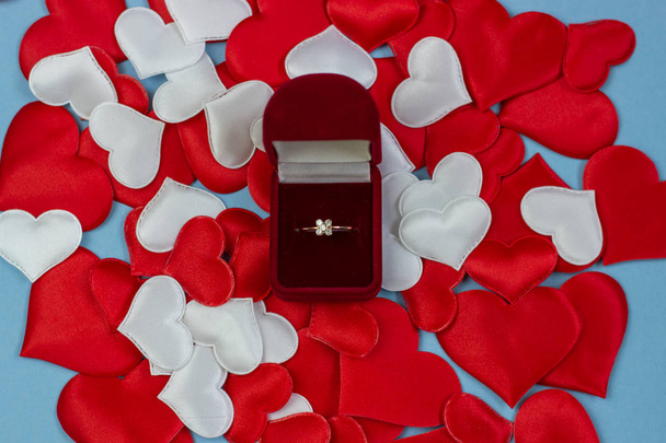 Rengas punaisessa laatikossa taustalla sydämet punainen ja valkoinen. Vihkisormus laatikossa. Avioliitto ehdotus käsite, Ystävänpäivä, Kansainvälinen naistenpäivä
. - Valokuva, kuva