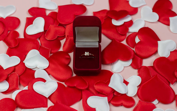 Ring in a red box on a background of hearts of red and white. Wedding ring in the box. Marriage proposal concept, Valentine's Day, International Women's Day. - Photo, image