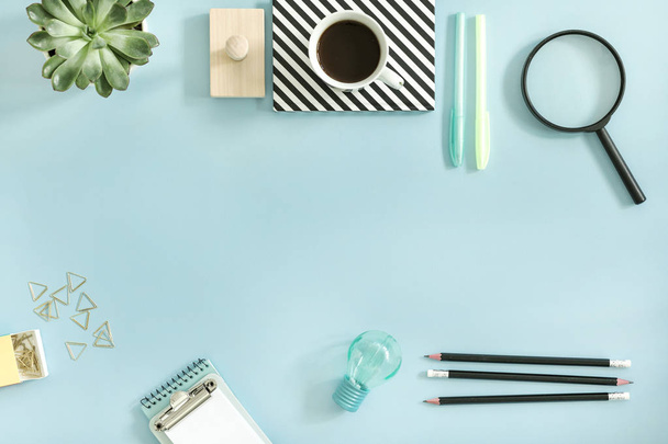 creative desk with school accessories, notebook, cup of coffee and green succulent on blue background - Φωτογραφία, εικόνα