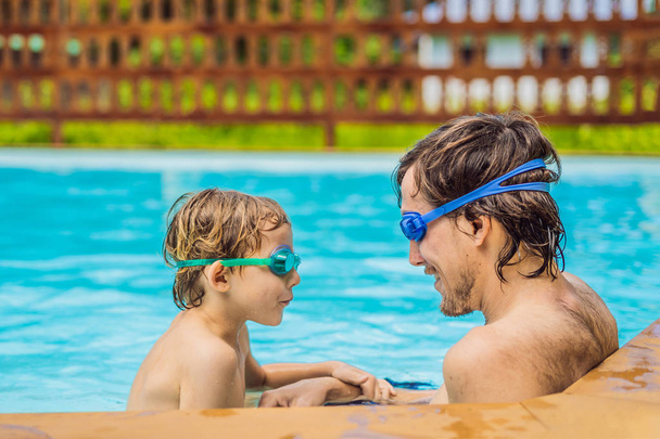 Dad and son in swimming Goggles have fun in the pool - 写真・画像