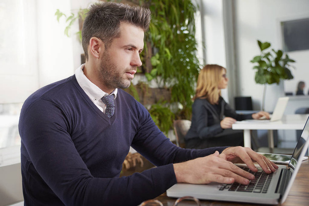 Снимок финансового помощника бизнесмена, сидящего за столом офиса и работающего над ноутбуком
 - Фото, изображение