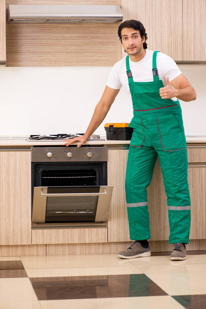 台所でオーブンを修理する若い請負業者  - 写真・画像