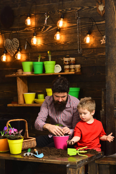 Father and son. happy gardeners with spring flowers. Flower care watering. Soil fertilizers. bearded man and little boy child love nature. Family day. Greenhouse. I love flowers - Foto, immagini