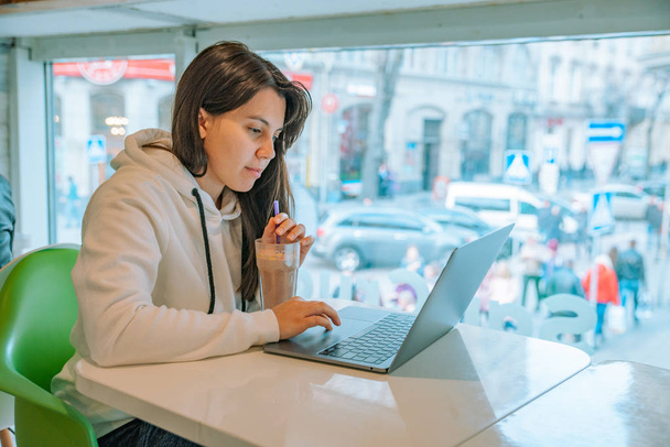 jeune jolie femme assise dans un café avec ordinateur portable et boire du chocolat chaud. travailler sur le bureau
 - Photo, image