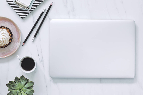 A design márvány asztal tetejét laptop, notebook csésze kávé, sütemény, zamatos és jegyzetek. Koncepció a szociális média és a honlap. - Fotó, kép