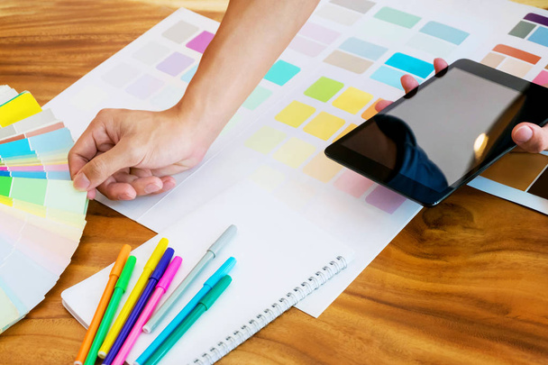 Femme d'affaires créative utilisant une tablette et travaillant sur des tableaux de couleurs sur bureau dans un bureau moderne
 - Photo, image