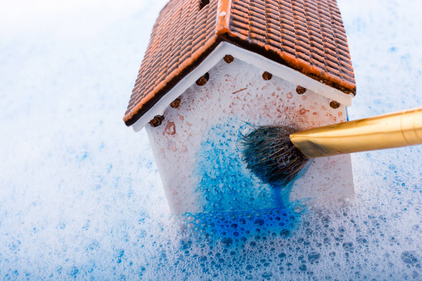 Pequeña casa modelo y un pincel de pintura en agua espumosa
 - Foto, Imagen